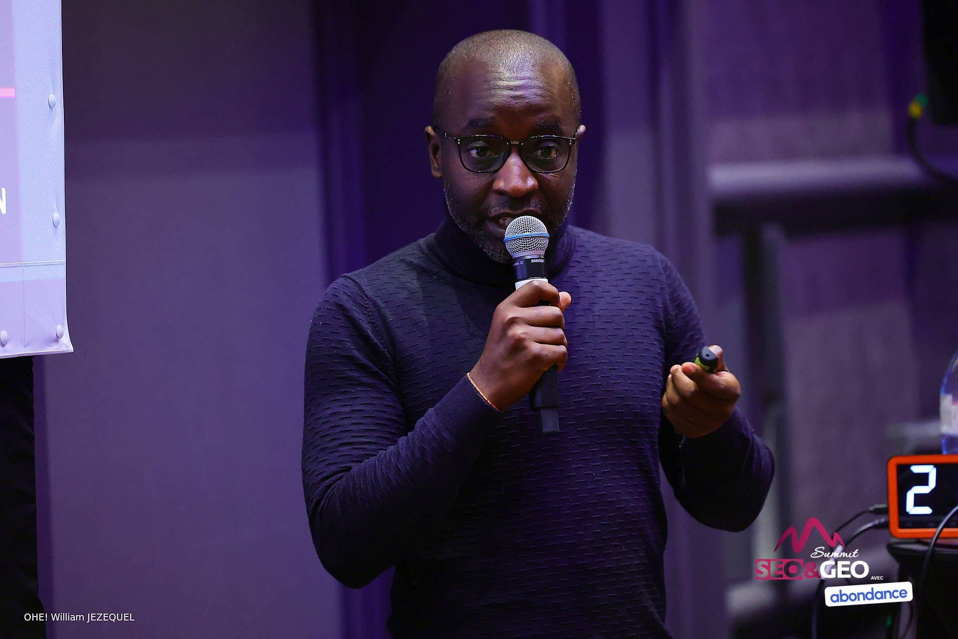 Hervé Nguetsop sur scène au SEO & GEO Summit 2026, pendant sa conférence « Vends-moi ce caillou »